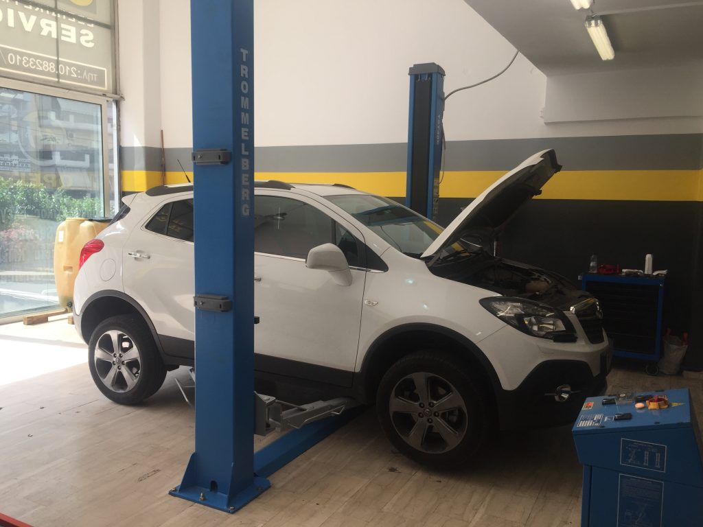 Λευκό Opel σε ανυψωτικό, με ανοιχτό καπό, στο συνεργείο